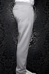 Men's light gray jogging pants side view with elastic waistband, drawcord, welt pockets, and full leg by Au Noir