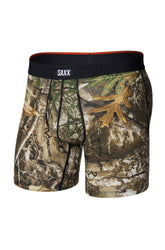Men's brown woodland camouflage boxer underwear with pouch seams and black SAXX waistband, isolated front view