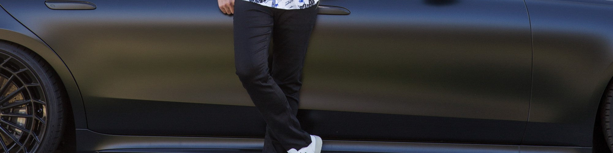 Un jeans propre de la marque Au noir de couleur noir devant une voiture de luxe