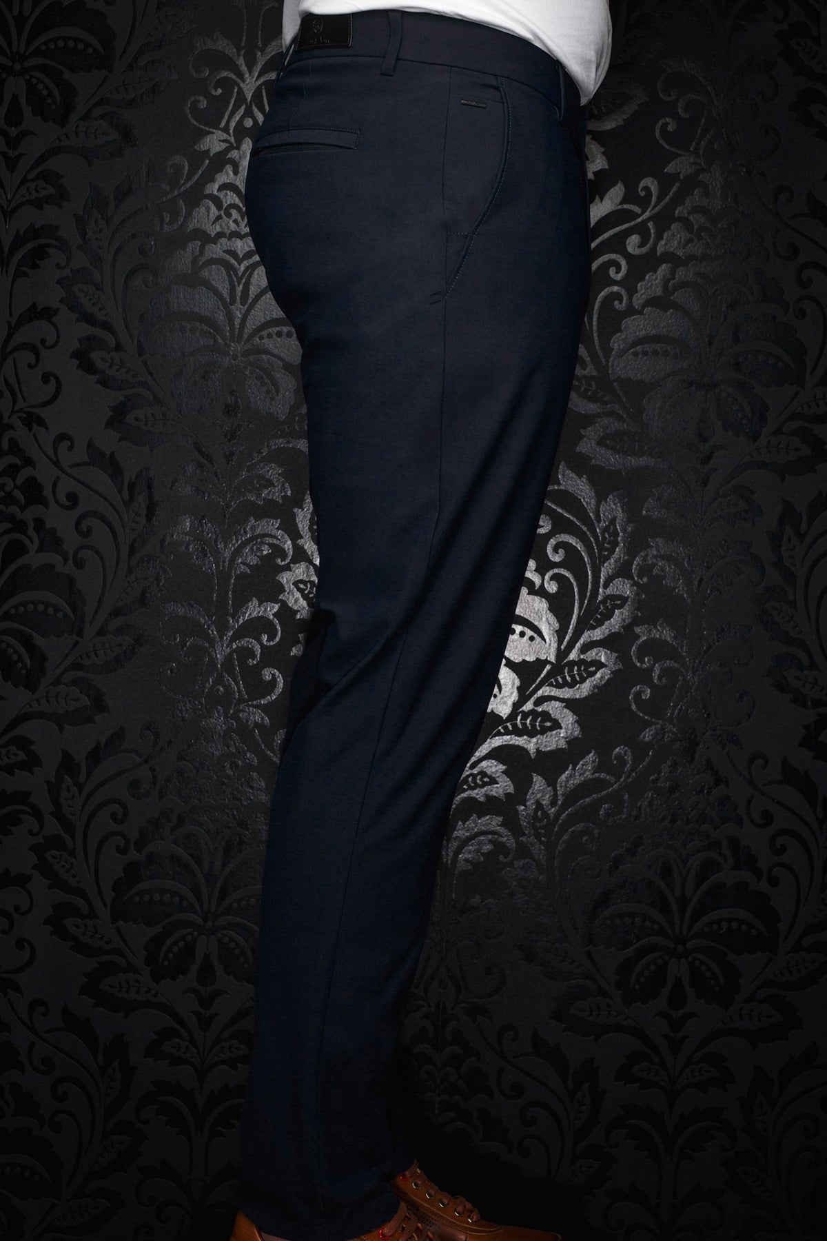 Men's navy pants shown from the side, with belt loops, welt pocket, and small metal logo plate by Au Noir