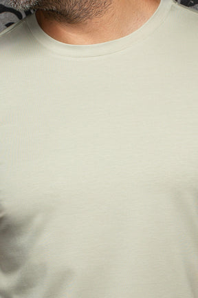 Au Noir men's pale sage green crewneck Short-sleeve T-Shirt showing ribbed collar and fine jersey texture, close-up