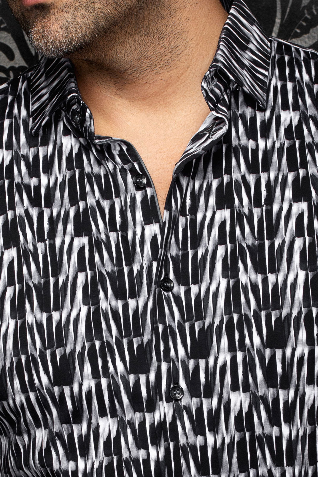 Au Noir men's black and white abstract print shirt showing spread collar, placket, and black buttons, close-up