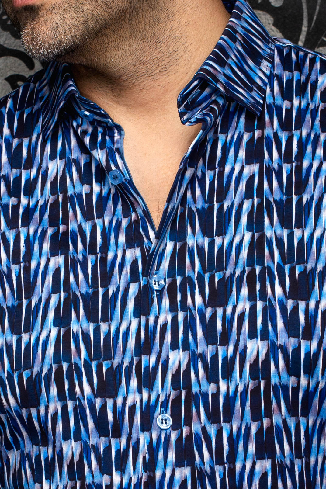 Au Noir men's blue abstract print button-up shirt showing the spread collar and blue buttons, close-up