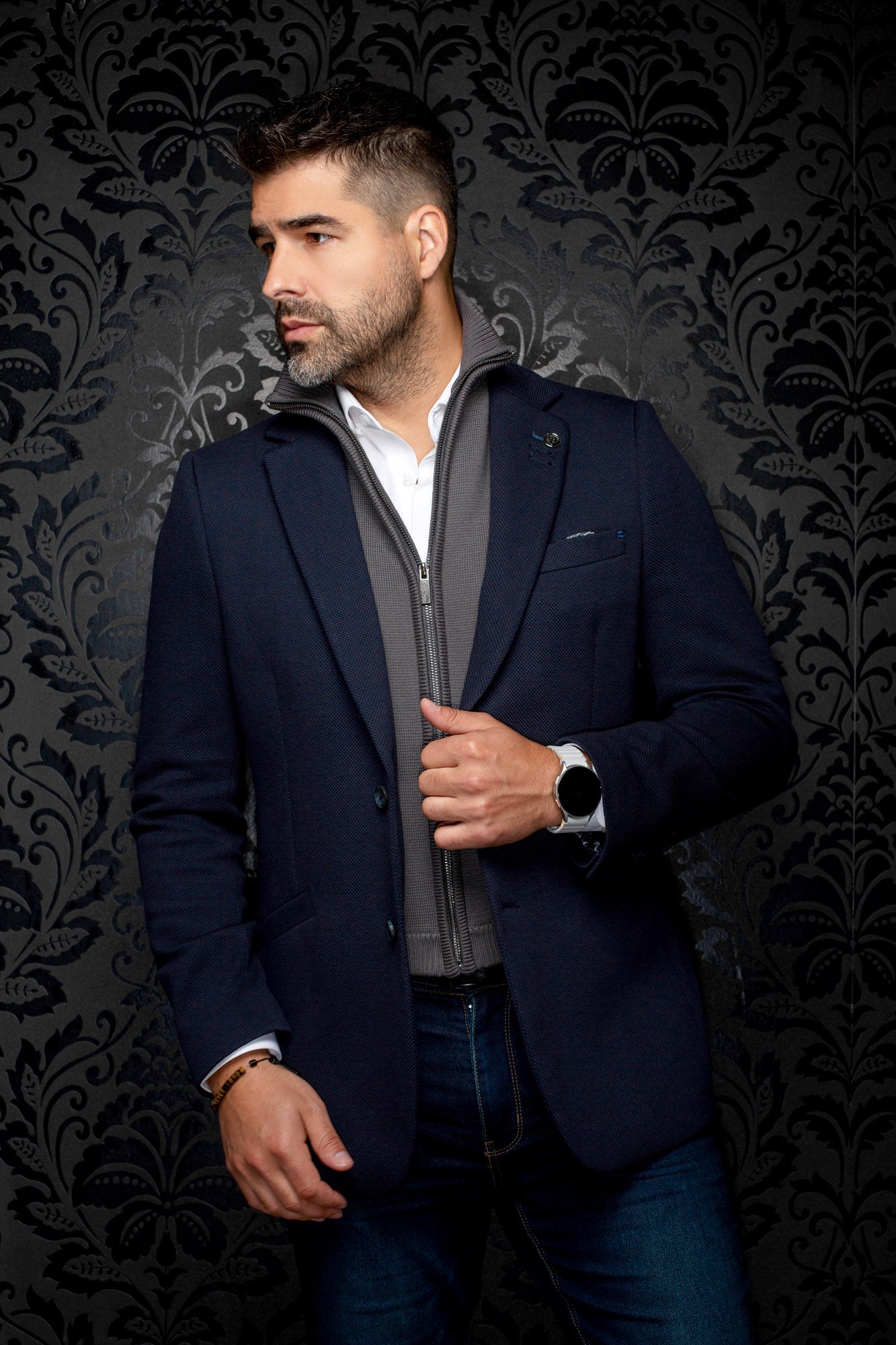 Men's slight side view of a navy textured blazer with a visible gray zip-front inner layer by Au Noir