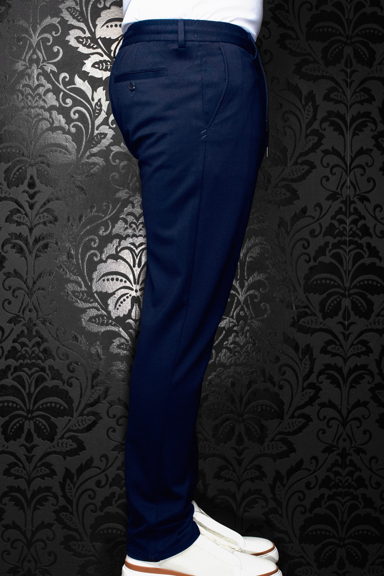 Men's navy pants shown from the side, with belt loops and a buttoned back welt pocket by Au Noir