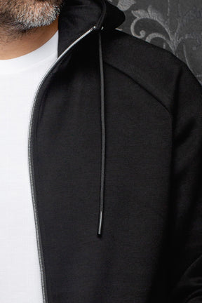 Au Noir men's black hooded zip sport jacket with silver zipper, drawcord, and subtle textured front panel, close-up