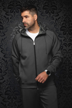 Men's dark gray hooded zip sport jacket on model, front view with black zipper, drawcords, and banded hem by Au Noir