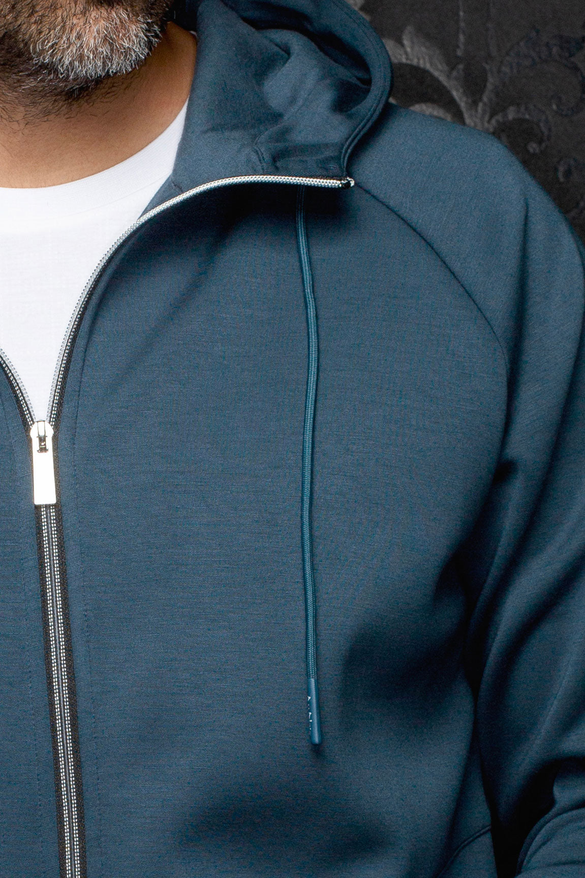 Au Noir men's teal hooded zip sport jacket showing silver zipper, drawstring, and raglan seam, close-up