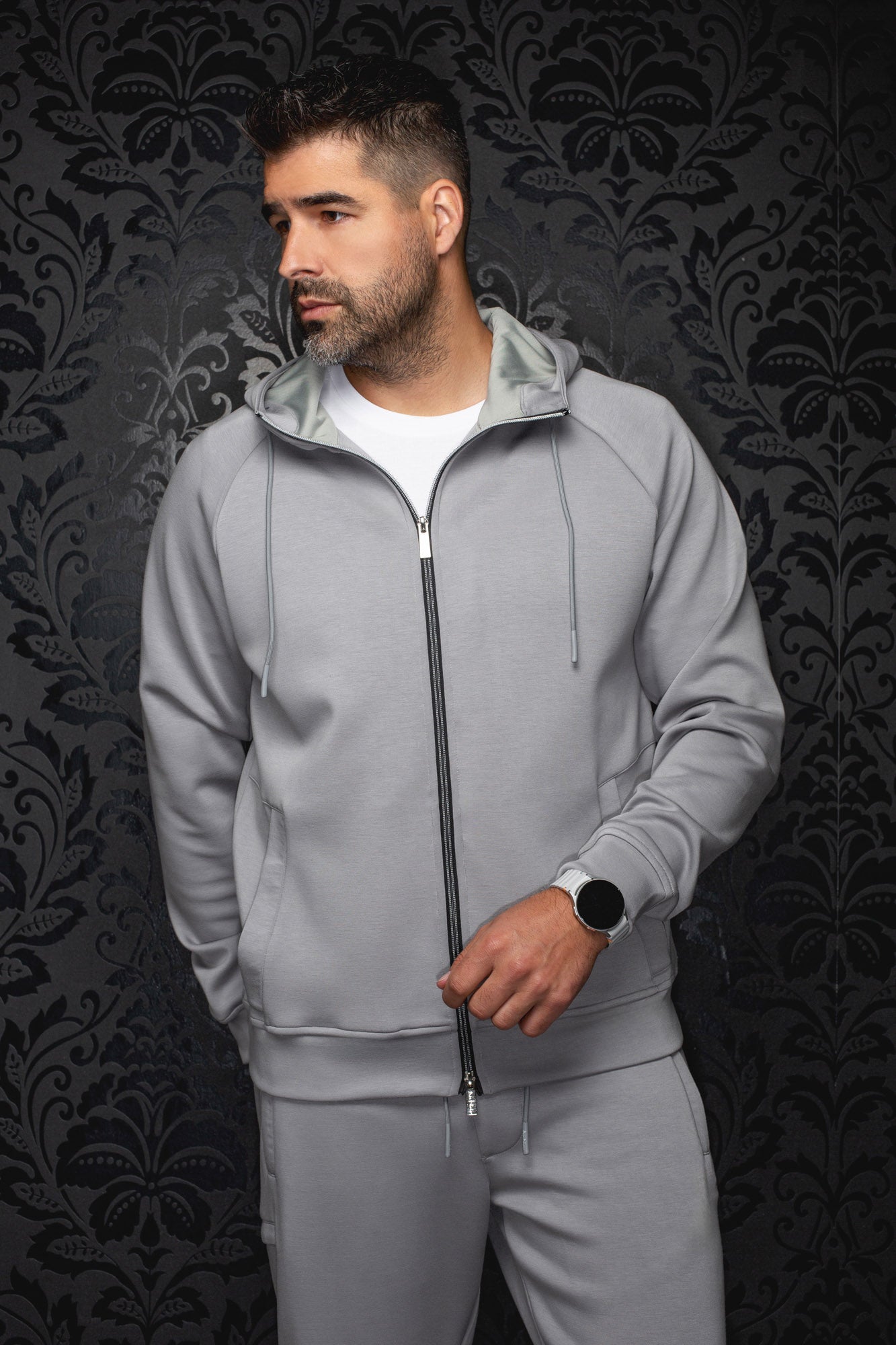 Men's light gray zip sport jacket shown from front, with black zipper, drawcords and split pockets by Au Noir