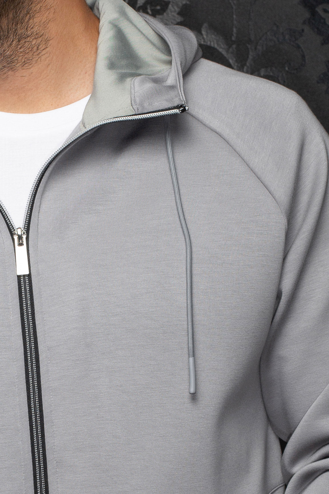 Au Noir men's light gray zip sport jacket with hood lining, black zipper tape and drawcord detail, close-up