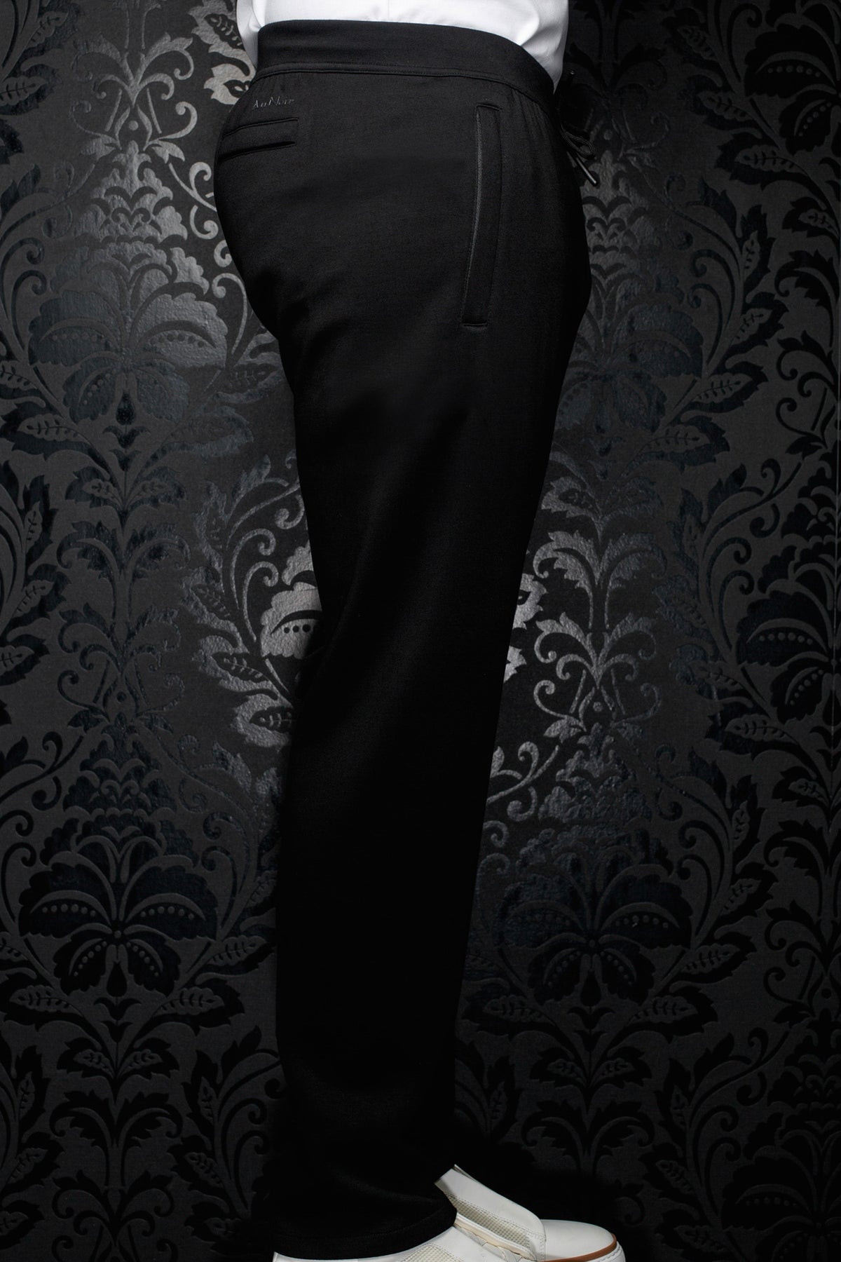 Side view of men's black jogging pants with elastic waistband, drawstring and vertical pocket detail by Au Noir