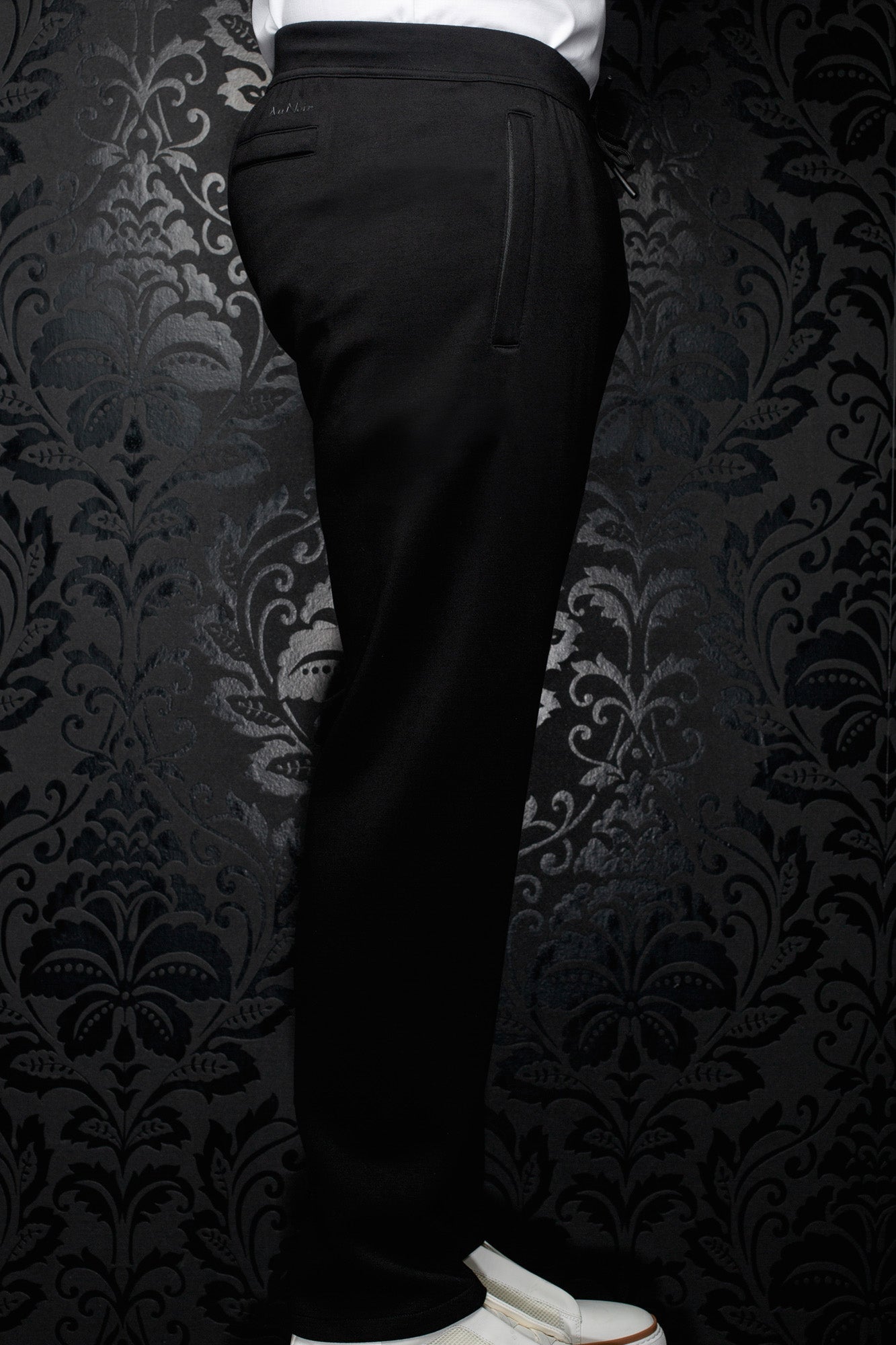 Side view of men's black jogging pants with elastic waistband, drawstring and vertical pocket detail by Au Noir