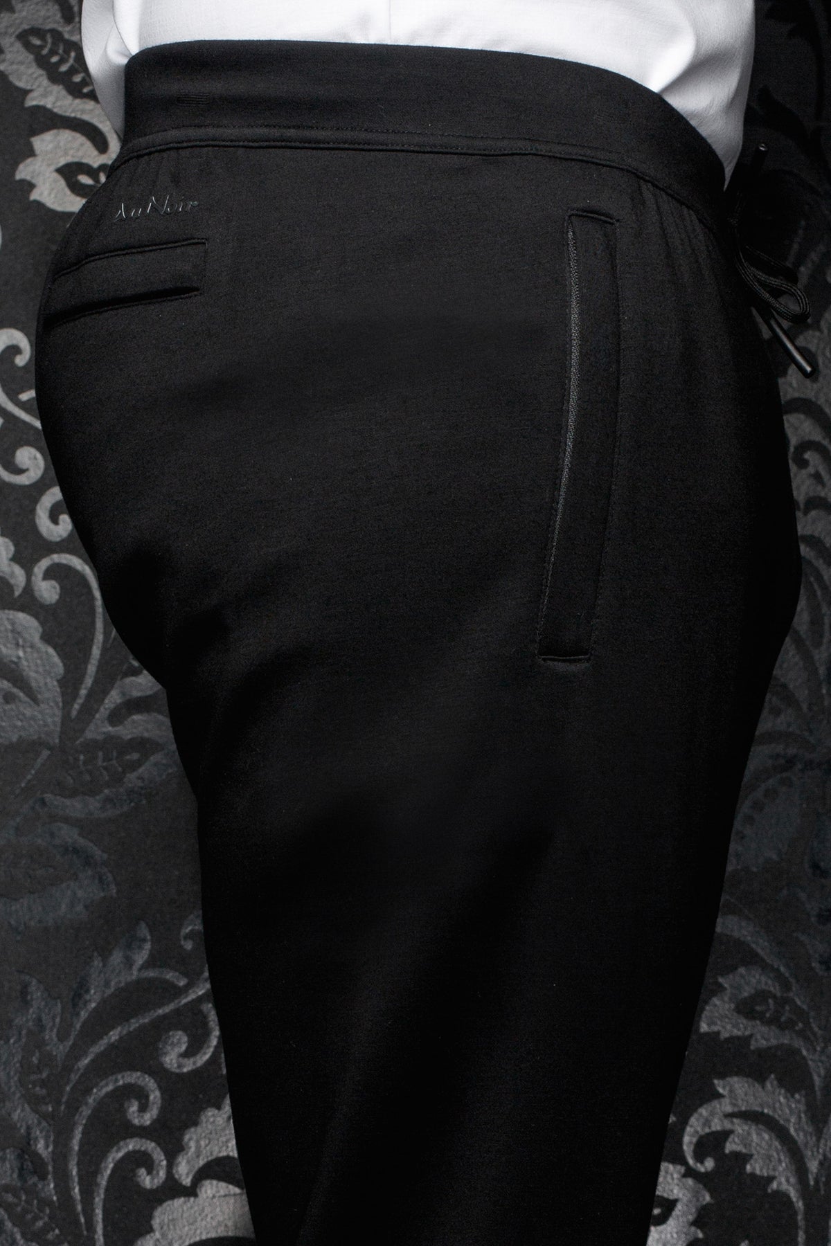 Au Noir men's black jogging pants with wide waistband, back welt pocket and tonal logo, close view