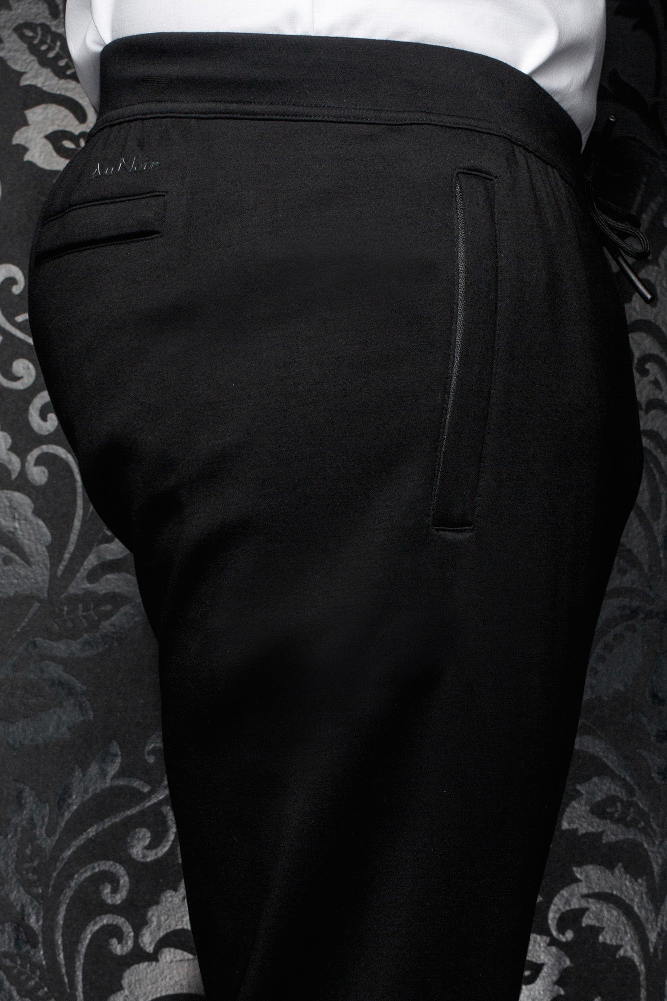 Au Noir men's black jogging pants with wide waistband, back welt pocket and tonal logo, close view