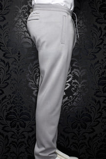 Men's light gray jogging pants side view with elastic waistband, drawcord, welt pockets, and full leg by Au Noir