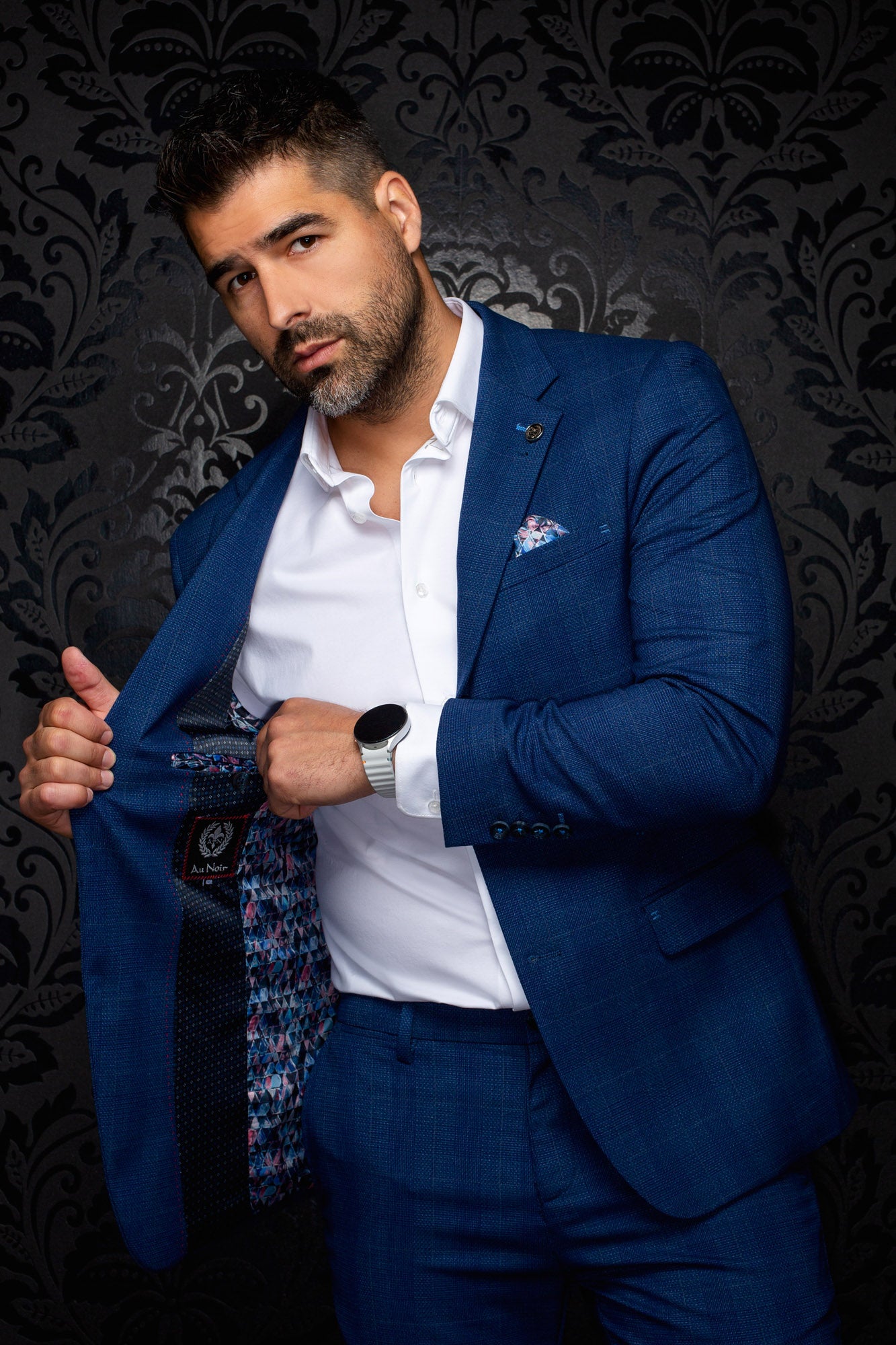 Men's angled view of a blue textured blazer showing multicolor patterned lining and interior label, detail view by Au Noir