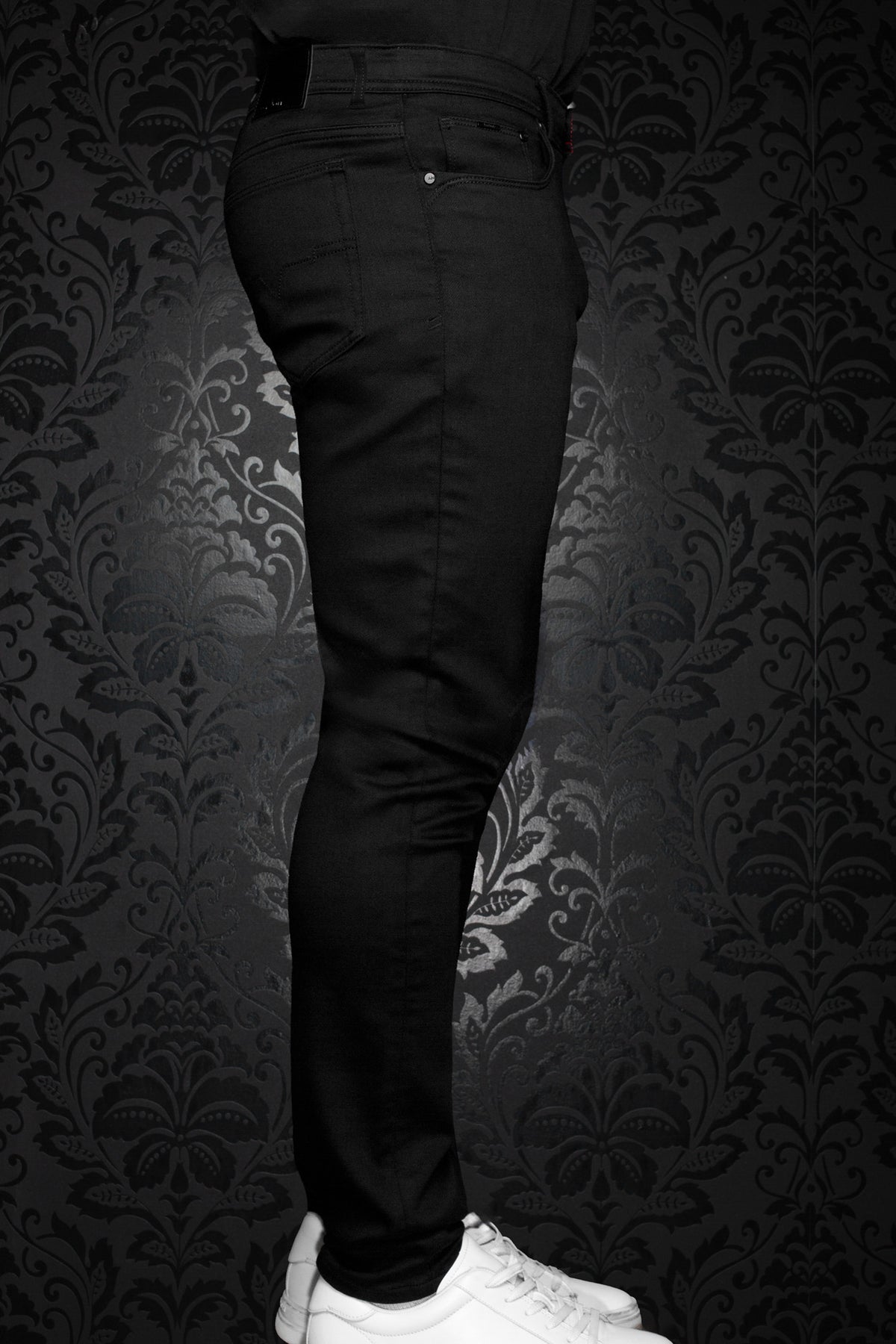 Au Noir men's black slim jeans on model, with front pocket, belt loops, and narrow leg, side view