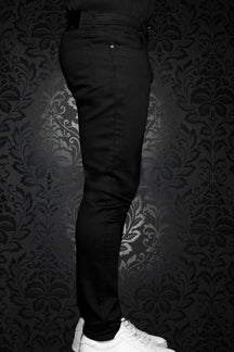 Au Noir men's black slim jeans on model, with front pocket, belt loops, and narrow leg, side view