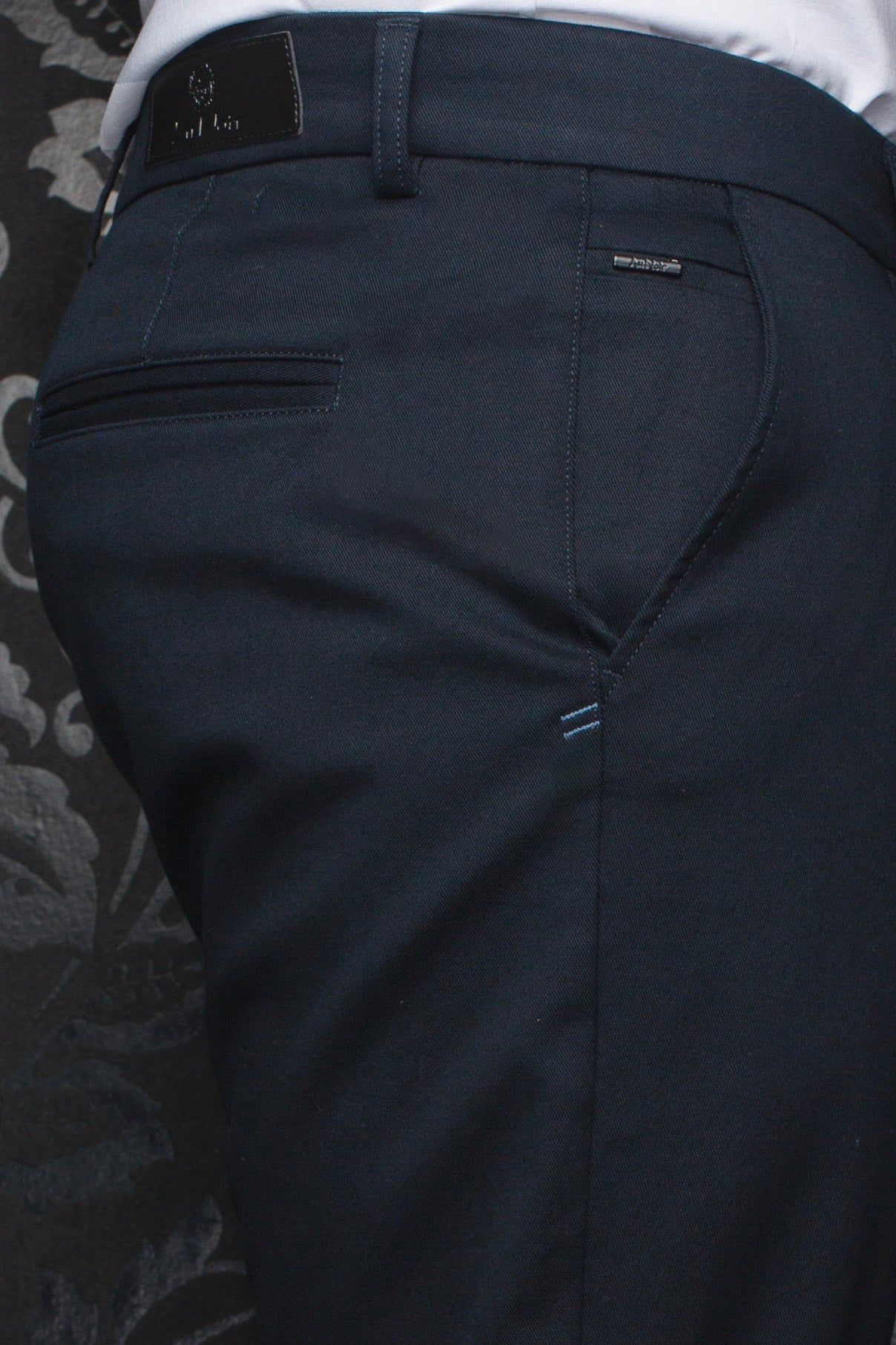 Au Noir men's navy chino pants back waistband, welt pockets, logo patch, and light blue stitching, close-up