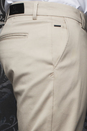 Au Noir men's beige chino pants with back welt pocket, belt loops, and black logo patch, close-up