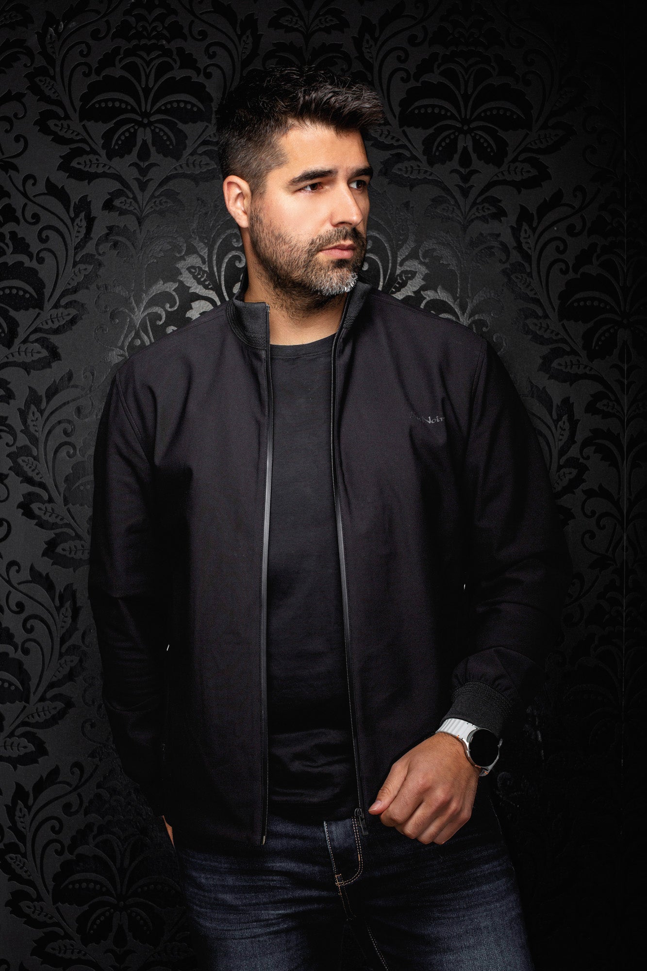 Au Noir men's black bomber jacket worn open, showing ribbed stand collar and gray zipper trim, front view