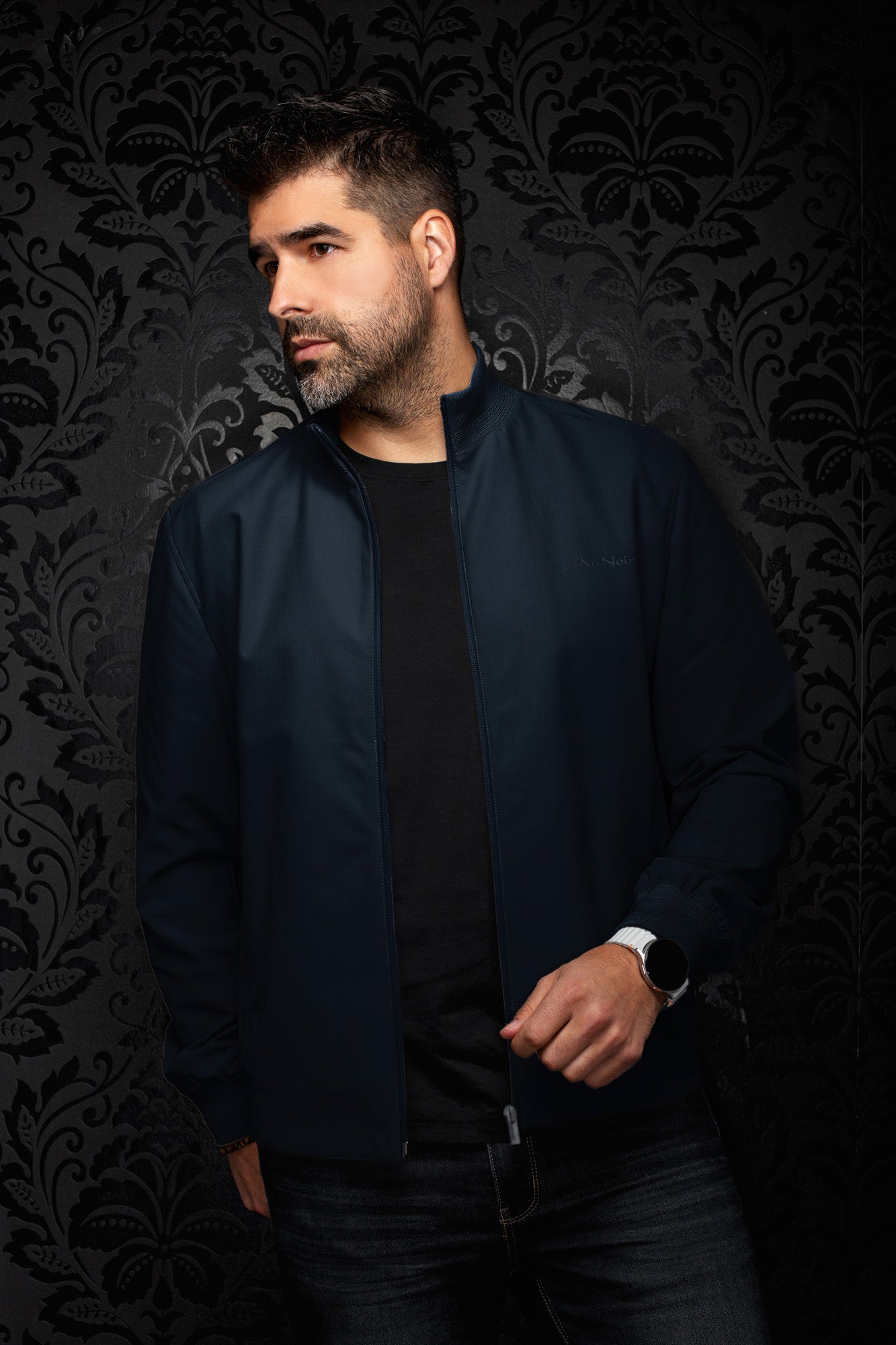Au Noir men's navy bomber jacket on model, open front zipper, ribbed cuffs and subtle tonal chest logo