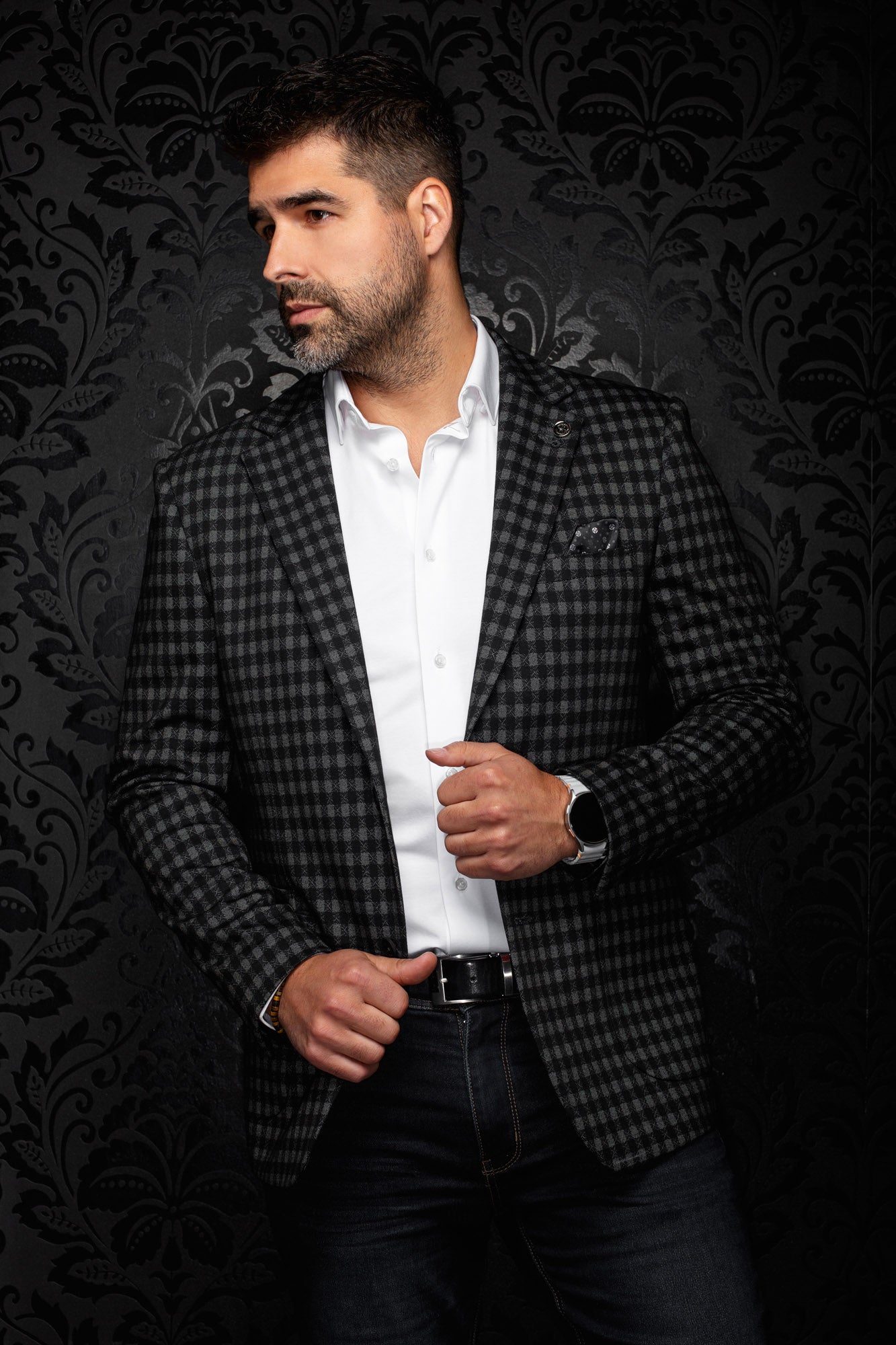 Men's slight angled front view of black and gray check blazer with lapel pin and lower pockets by Au Noir