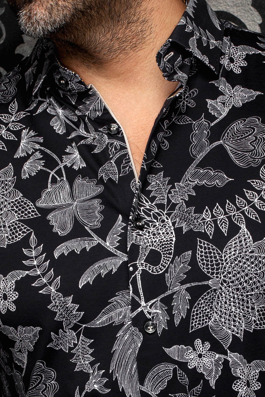 Au Noir men's collar and placket on black shirt with white floral line print and black buttons, close-up