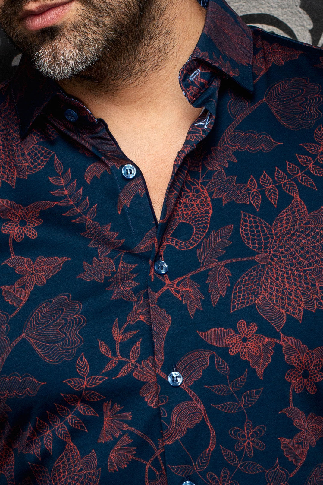 Close-up of men's navy floral button-up shirt showing spread collar, blue buttons, and burgundy print by Au Noir