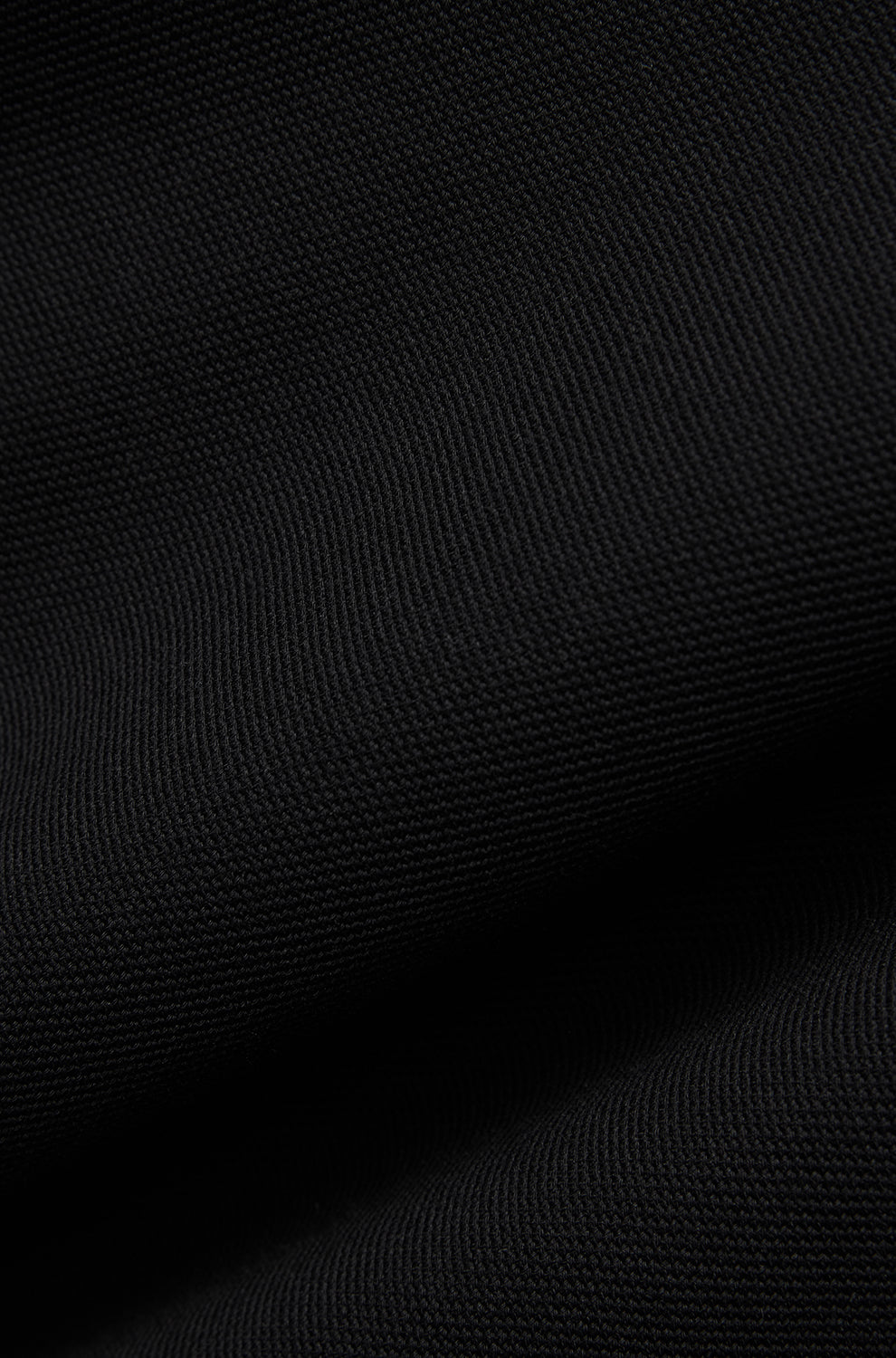 Psycho Bunny men's black textured polo fabric showing the fine knit surface and soft folds, close-up