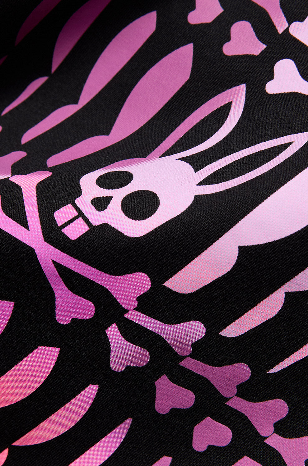 Close-up detail of men's pink Psycho Bunny skull-and-bones graphic printed on black Short-sleeve T-Shirt fabric