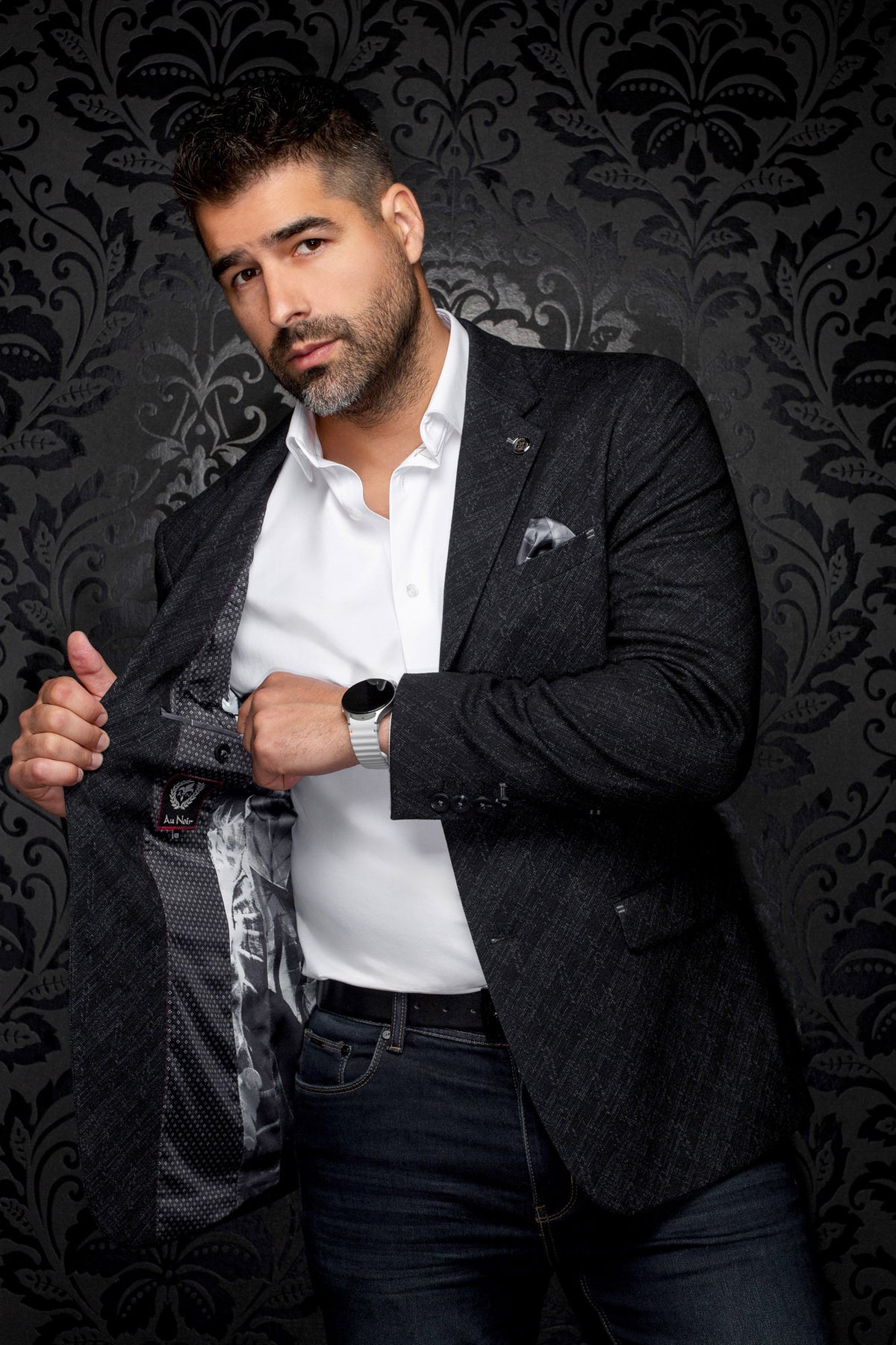 Men's angled view of a charcoal textured blazer opened to show dark patterned lining and logo label, detail view by Au Noir