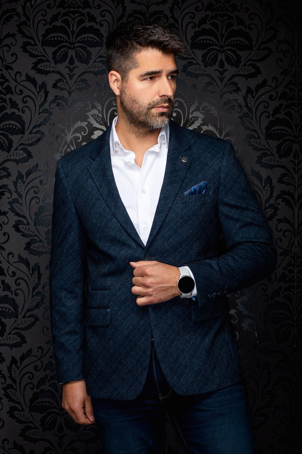 Au Noir men's angled front view of a navy textured blazer with notched lapels, flap pockets, and lapel pin
