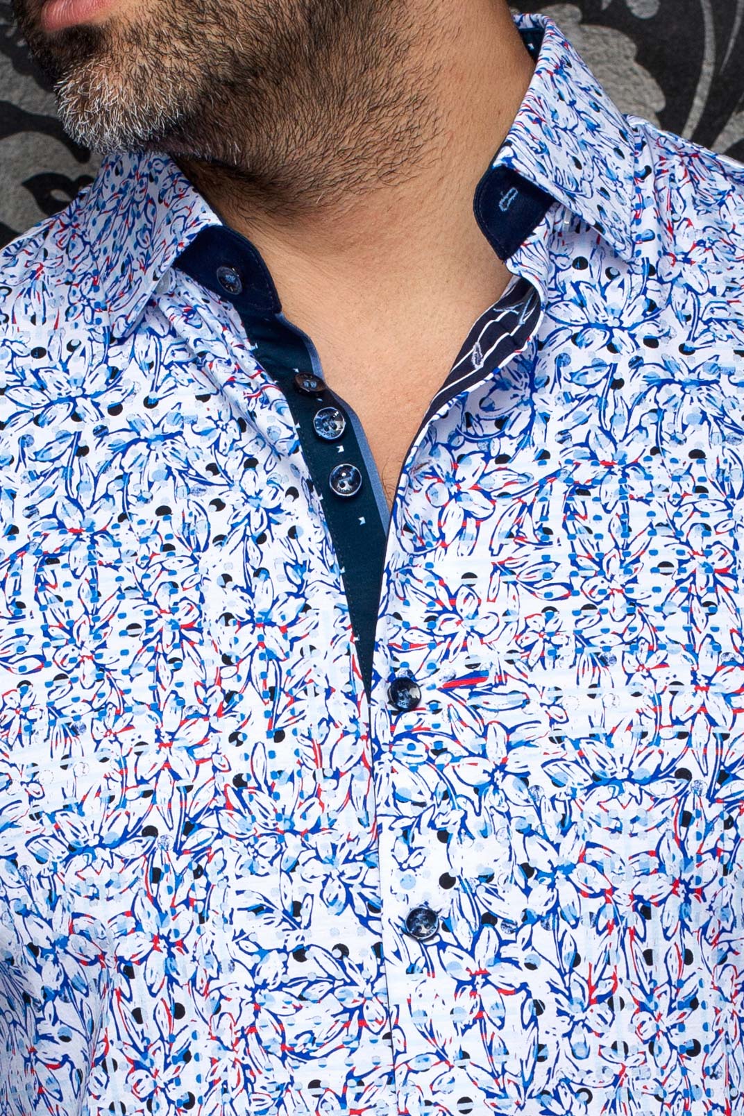 Gros plan du col de chemise florale blanche, patte marine, boutons foncés et motif bleu-rouge pour homme par Au Noir