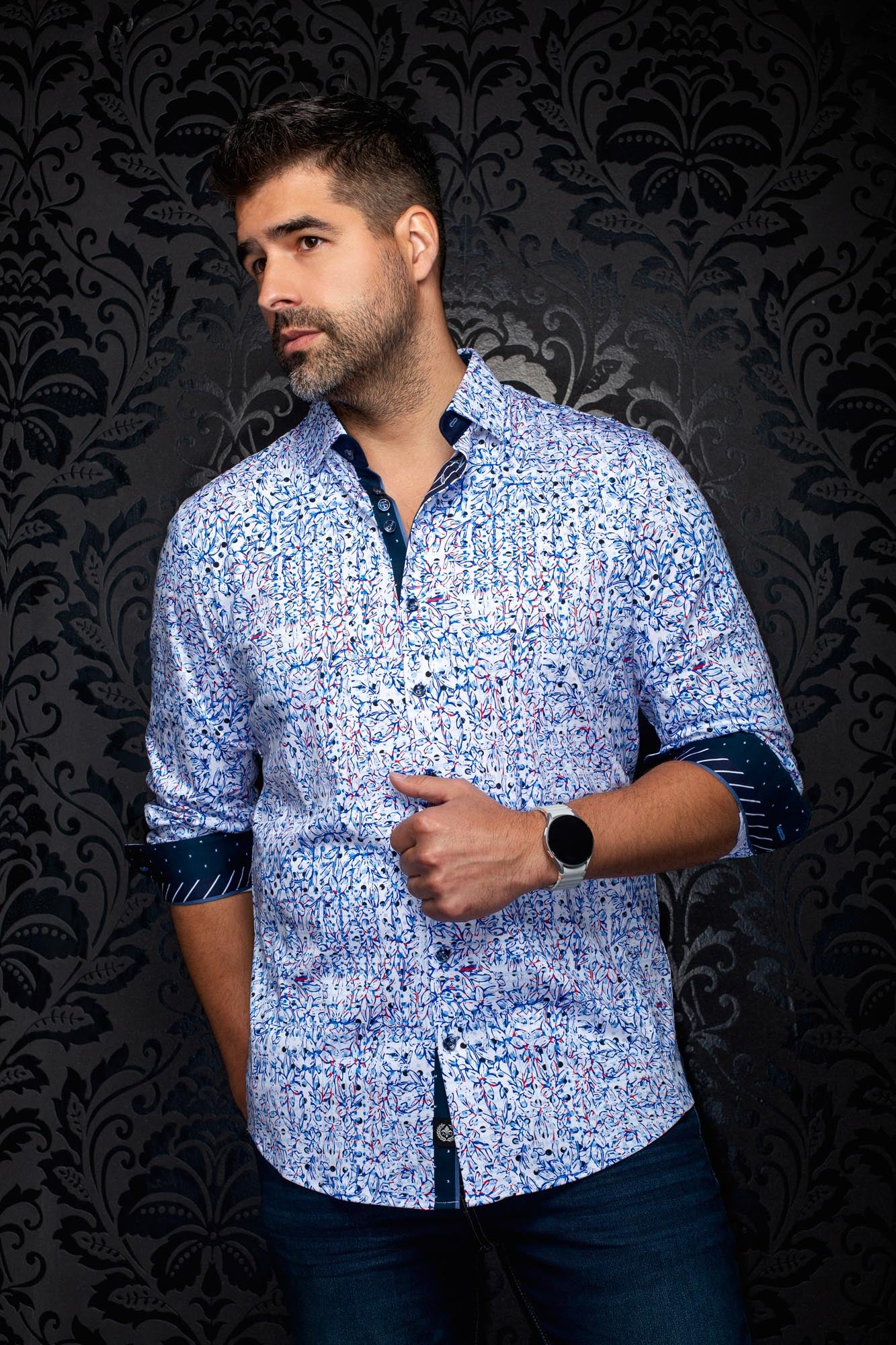 Vue en angle d’une chemise blanche florale à motif bleu et rouge avec poignets marine roulés pour homme par Au Noir