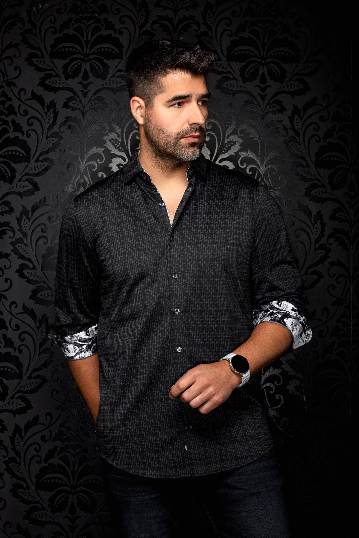 Au Noir men's angled model view of black patterned button-up shirt with rolled cuffs showing contrast print, side view