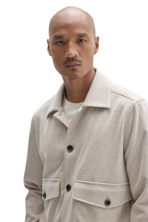 Close-up of men's cream textured jacket collar, flap pocket details and dark buttons by Robert Barakett