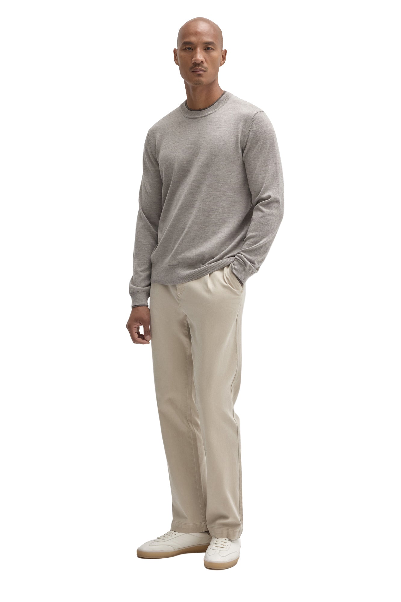 Men's full-body front view of a light grey crew neck long-sleeve knit sweater styled with beige pants by Robert Barakett