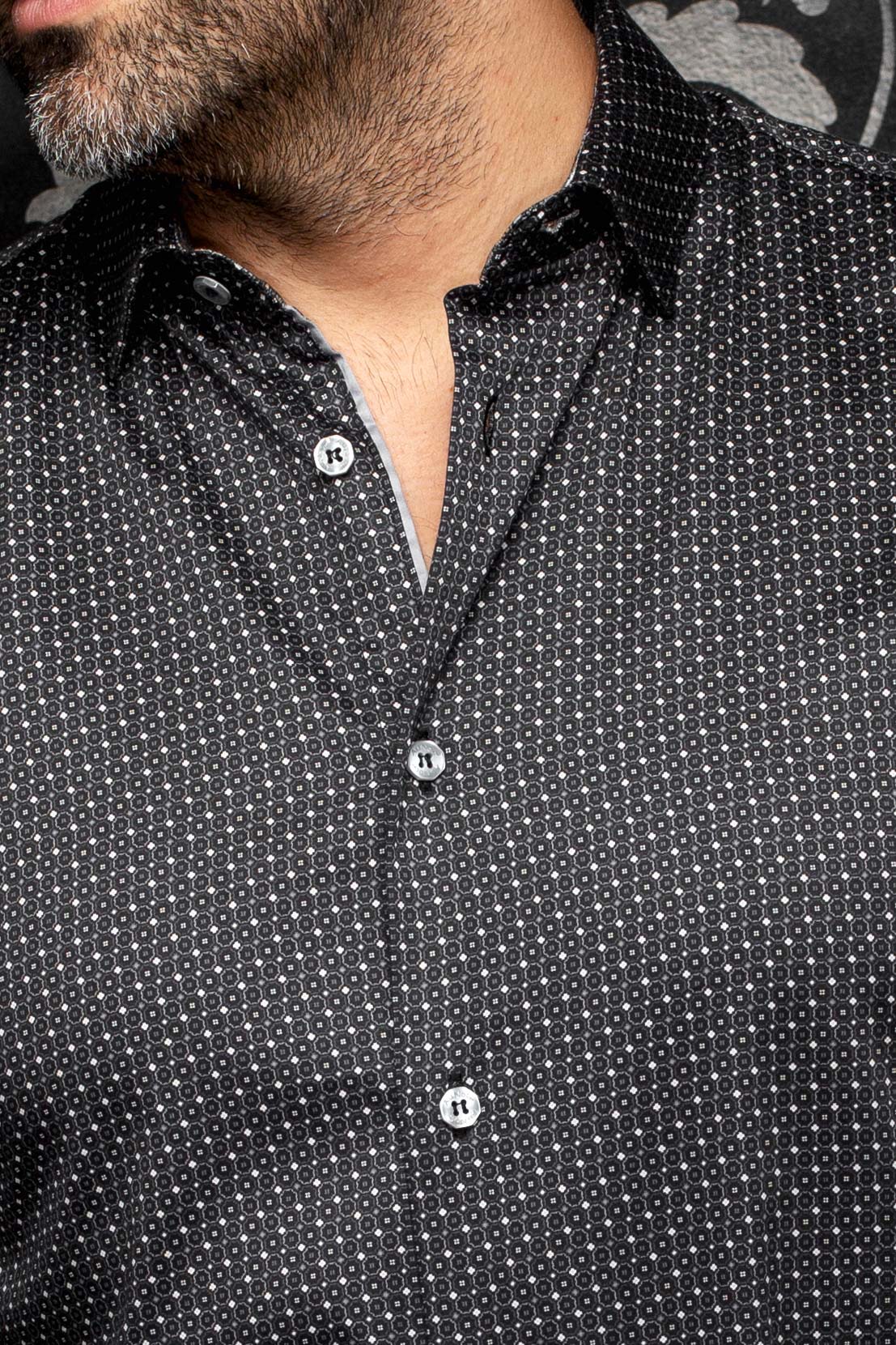 Gros plan d’une chemise noire à micro motif, col pointu, boutons gris et bordure intérieure pâle pour homme par Au Noir
