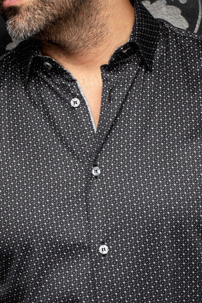 Gros plan d’une chemise noire à micro motif, col pointu, boutons gris et bordure intérieure pâle pour homme par Au Noir