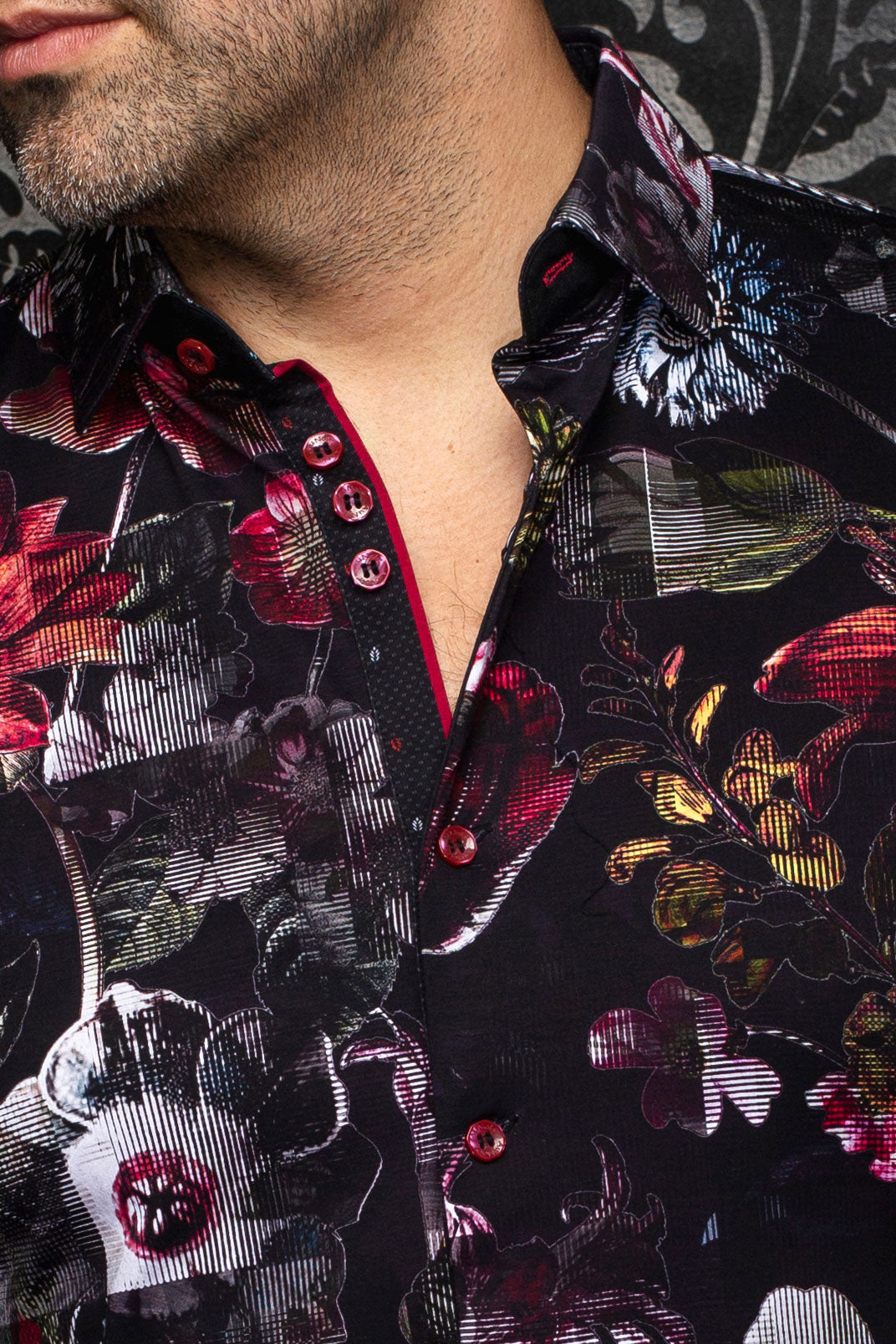Col d'une chemise noire fleurie, boutons rouges et patte contrastante pour homme par Au Noir, en gros plan