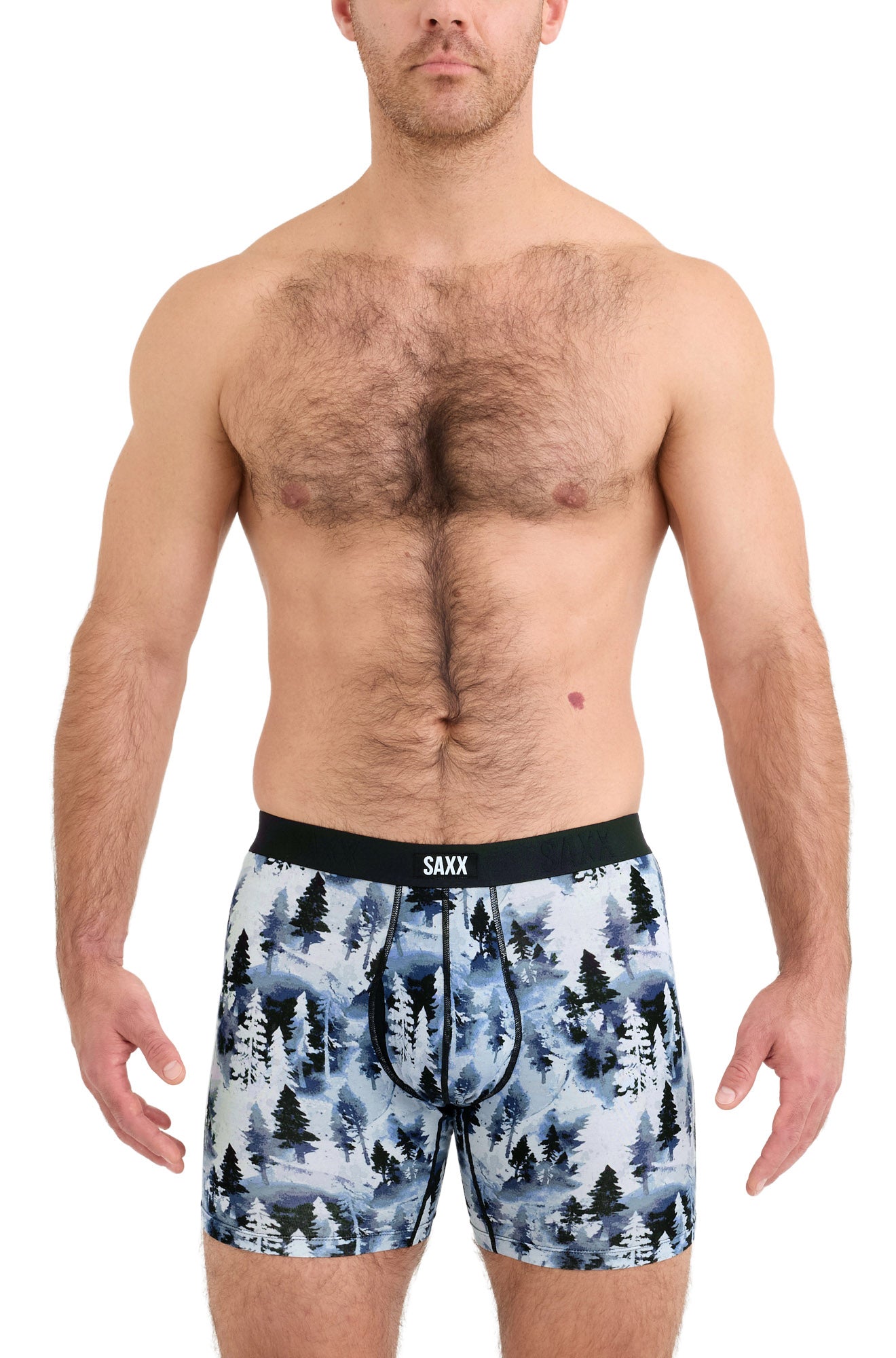 Men's model front view of blue forest-print boxer underwear with pouch seams and black logo waistband by Saxx