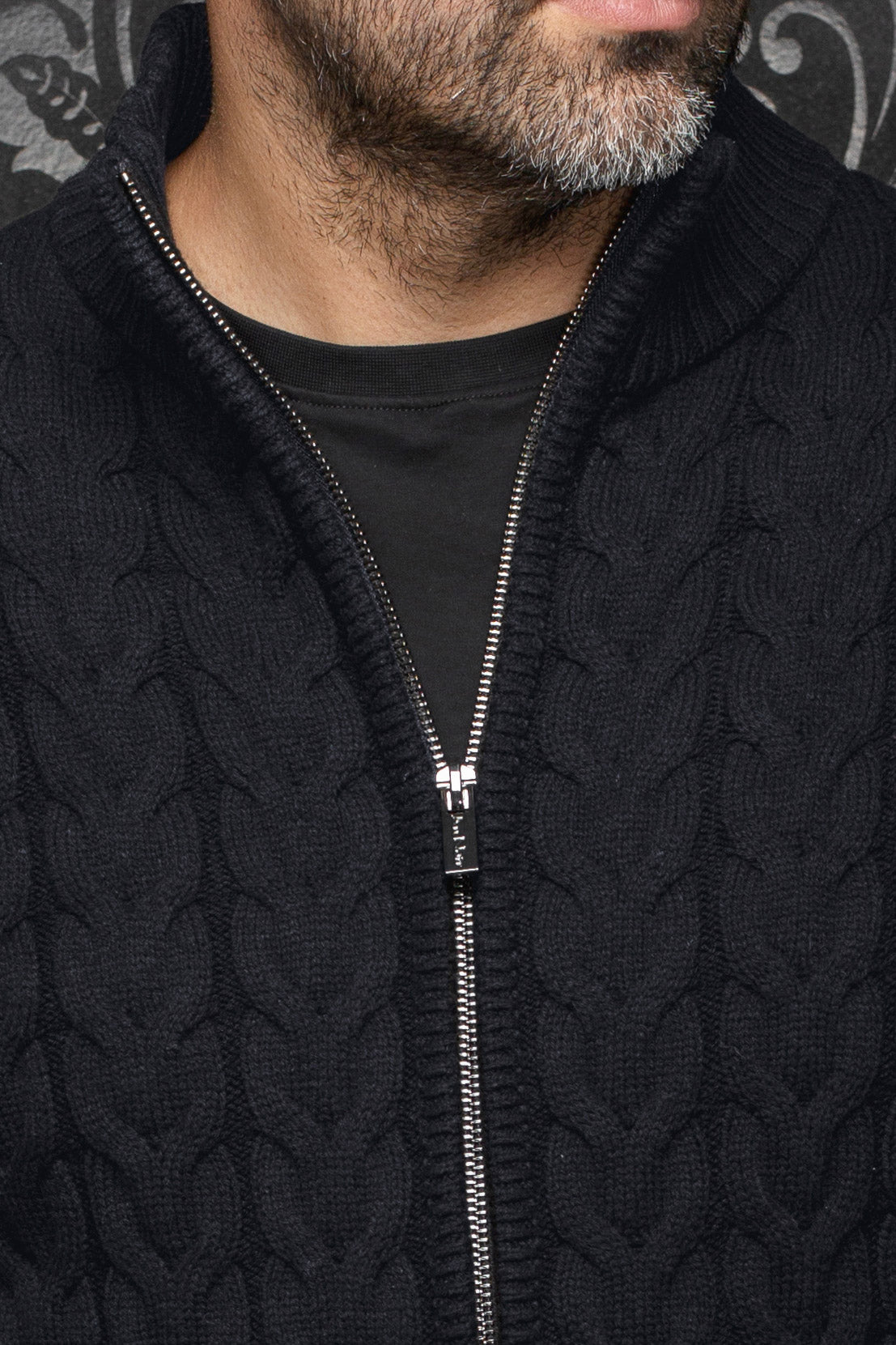 Au Noir men's black cable-knit zip merino jacket showing ribbed collar and silver-tone zipper, close-up
