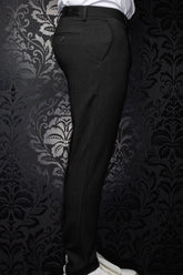 Men's black pants shown from the side, with belt loops, a back welt pocket and subtle woven texture by Au Noir
